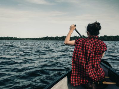 man in red and black plaid shirt sitting on boat during daytime